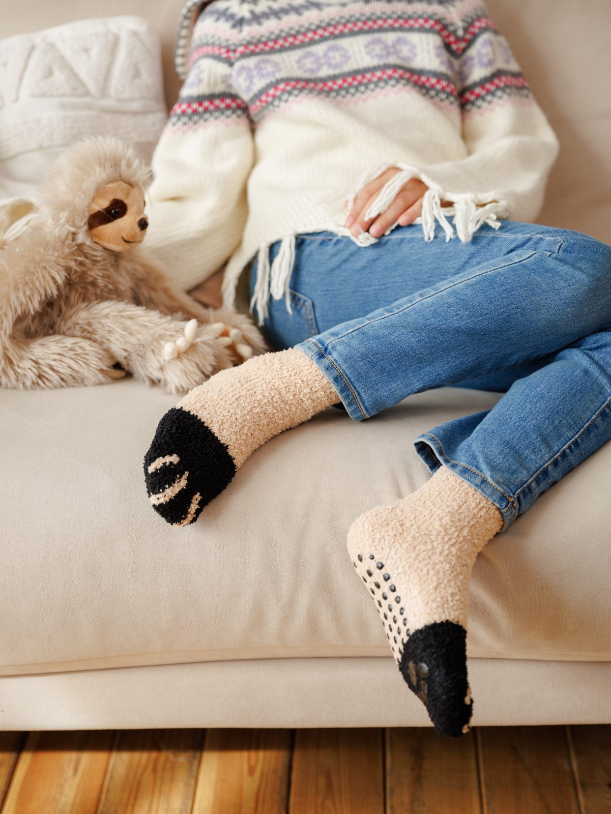Woman relaxing on a sofa wearing beige cat paw socks
