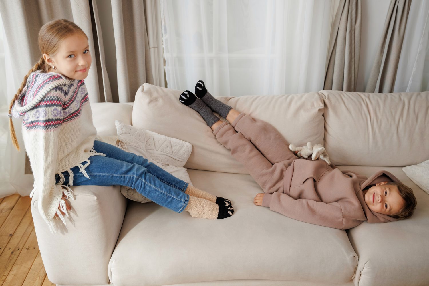 Two children lying on a sofa wearing cat paw socks