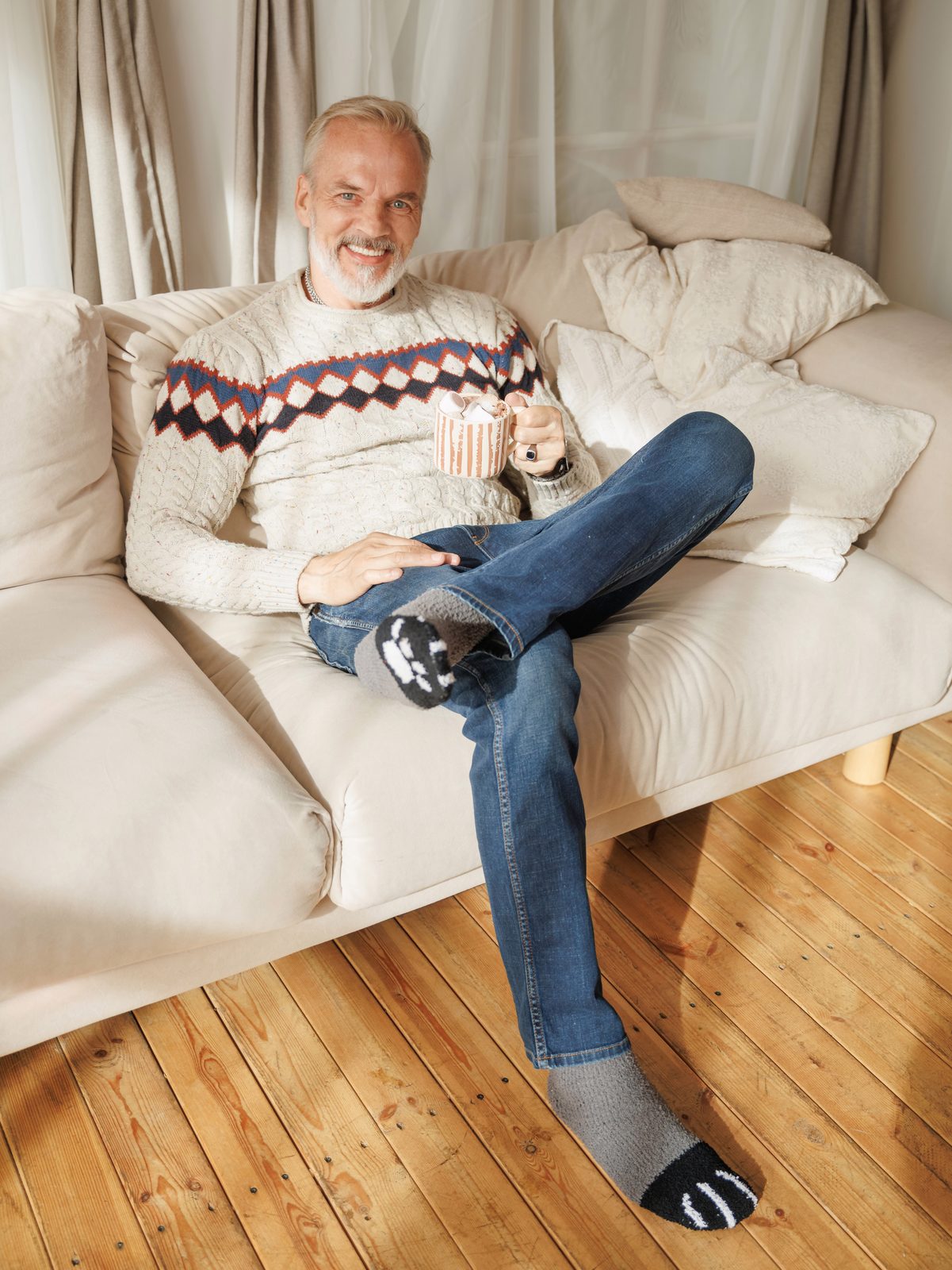 Smiling man on a sofa wearing cat paw socks