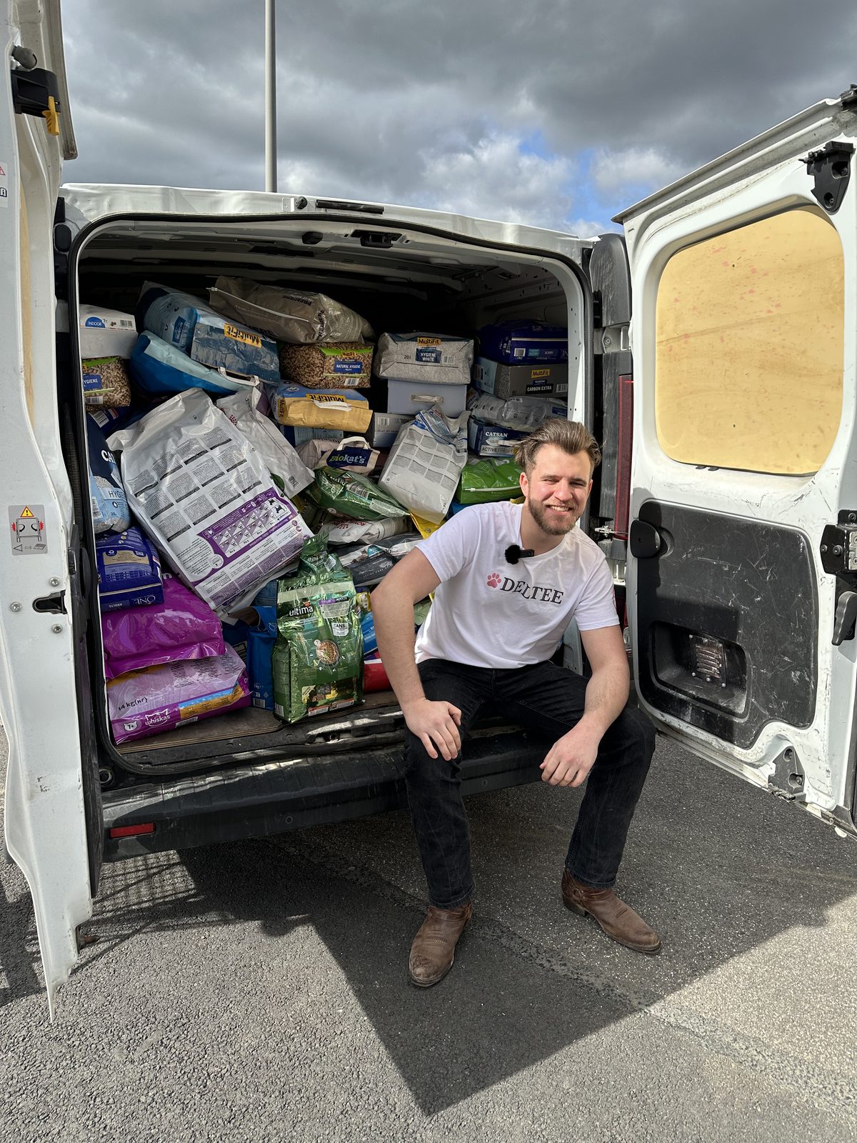 A member of the Deltee team sitting in a van packed with bags of cat food