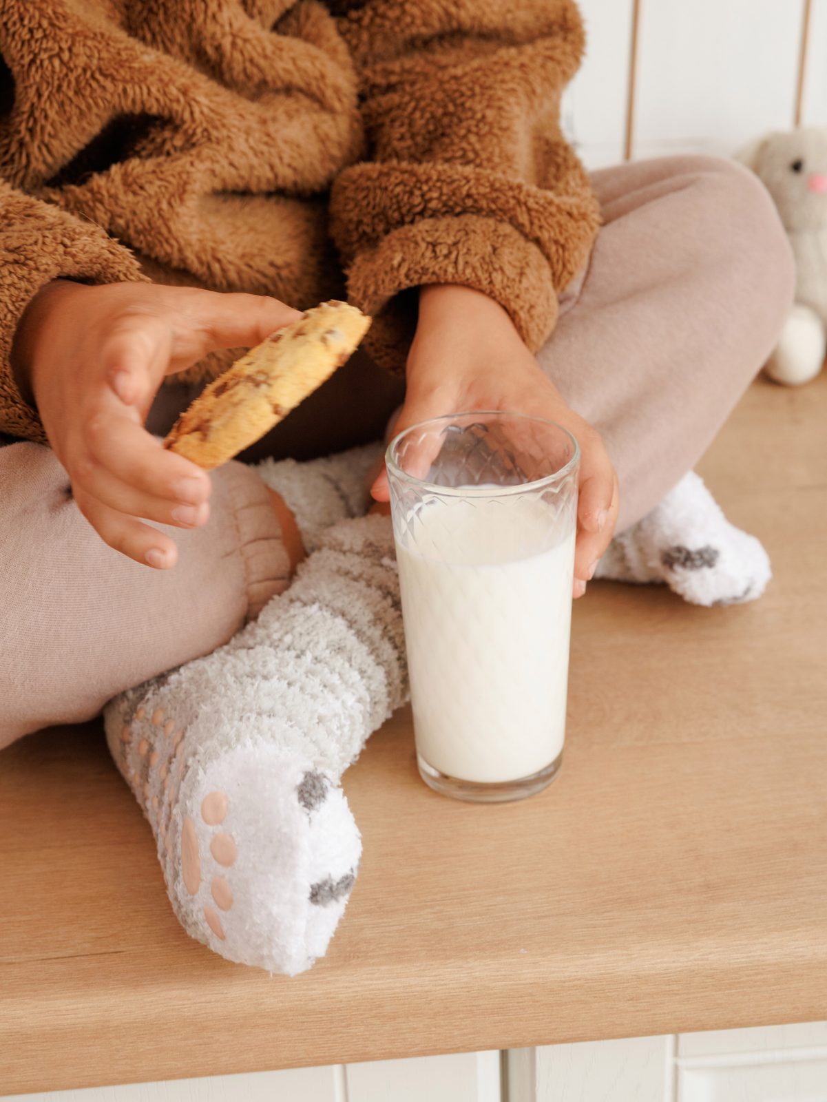 Sitting with a cookie and a glass of milk, wearing grey cat paw socks